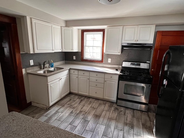 kitchen featuring black refrigerator, tasteful backsplash, stainless steel range, sink, and white cabinets