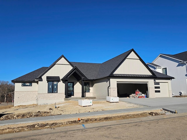 modern inspired farmhouse with driveway, a standing seam roof, stone siding, a garage, and board and batten siding