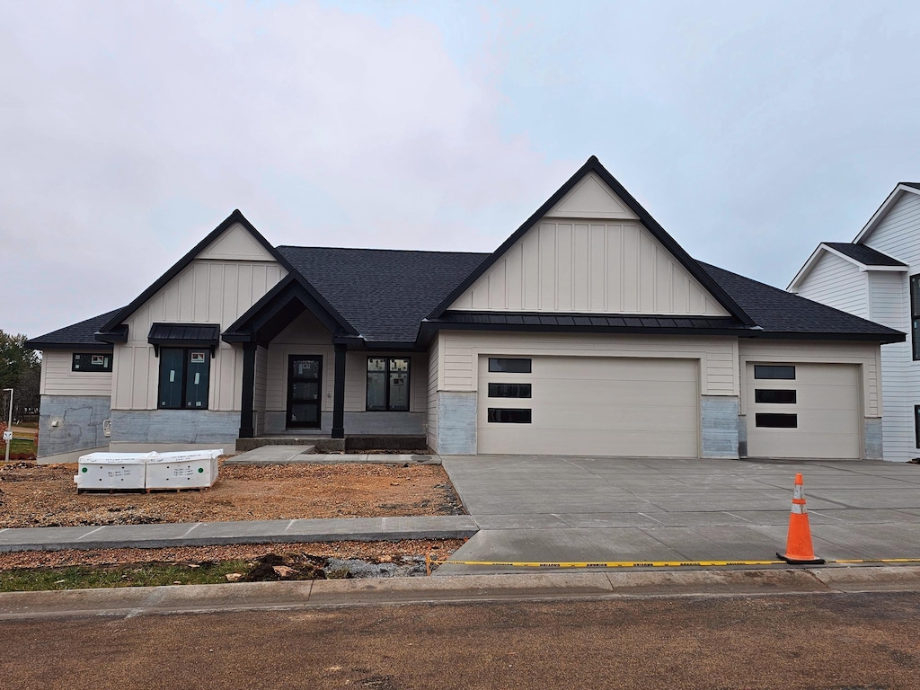 modern farmhouse style home featuring a standing seam roof, board and batten siding, driveway, and a garage