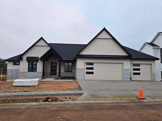 modern farmhouse style home featuring a standing seam roof, board and batten siding, driveway, and a garage