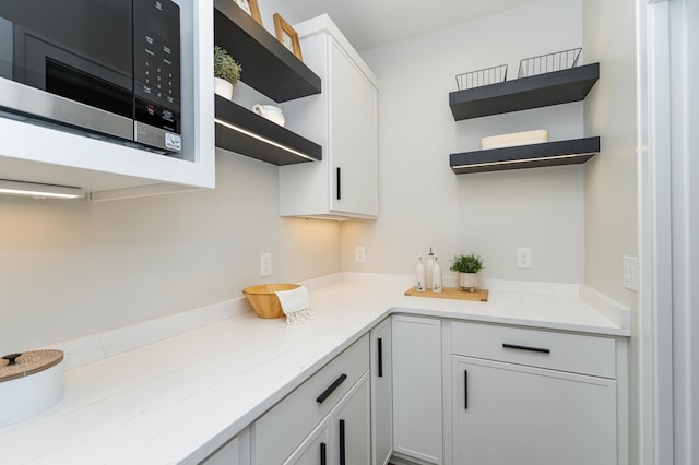 2665 Timber Oaks Rd SW, Rochester, MN 55902 - kitchen with open shelves, black microwave, light stone counters, and white cabinetry