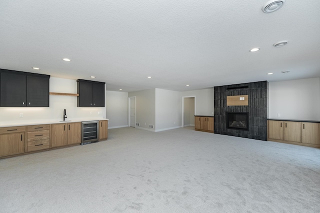 2665 Timber Oaks Rd SW, Rochester, MN 55902 - unfurnished living room with beverage cooler, wet bar, light colored carpet, a fireplace, and recessed lighting