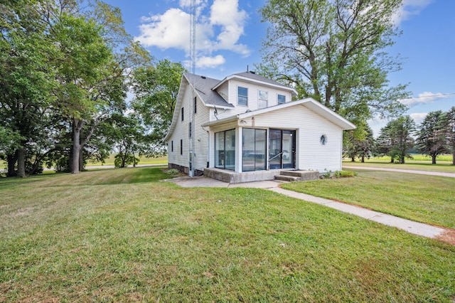 rear view of property featuring a yard and a sunroom