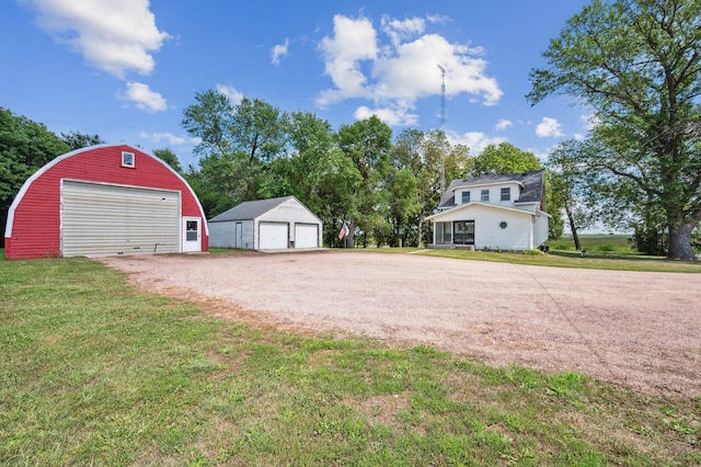 view of yard featuring a garage, an outbuilding, and driveway