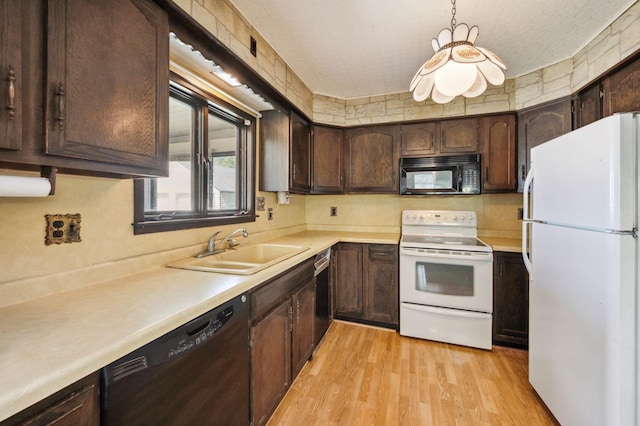 kitchen featuring black appliances, dark brown cabinets, a sink, and light wood-style floors