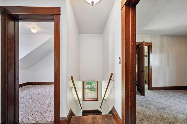 hall with carpet floors, baseboards, vaulted ceiling, and an upstairs landing