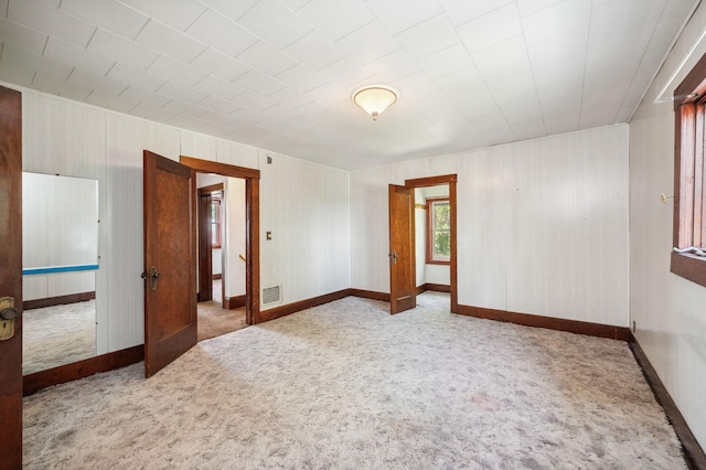 carpeted spare room with visible vents and baseboards