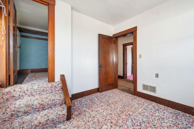 unfurnished bedroom with a closet, carpet, visible vents, and baseboards