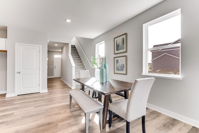 dining area featuring light wood-style flooring, stairs, and baseboards