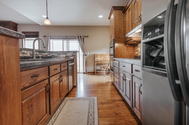 kitchen with pendant lighting, hardwood / wood-style floors, backsplash, sink, and appliances with stainless steel finishes