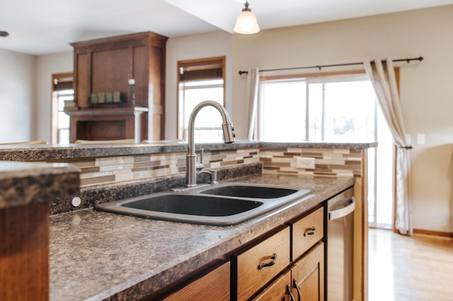 kitchen featuring light wood-type flooring, backsplash, sink, and stainless steel dishwasher