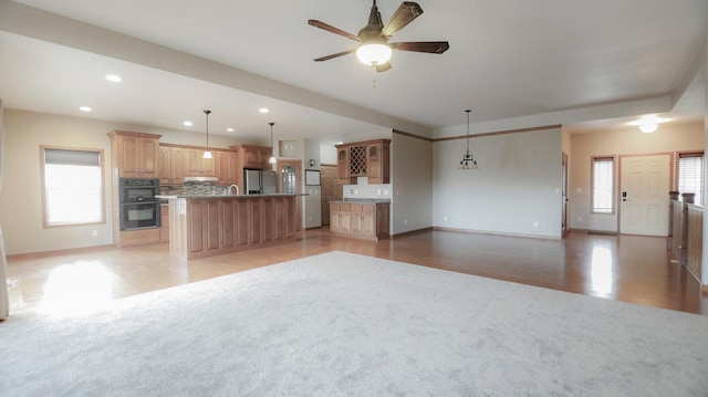 kitchen with a wealth of natural light, a center island, ceiling fan with notable chandelier, and light hardwood / wood-style flooring