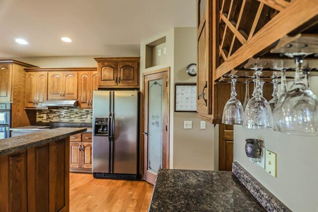 kitchen with stainless steel refrigerator with ice dispenser, light hardwood / wood-style flooring, and backsplash