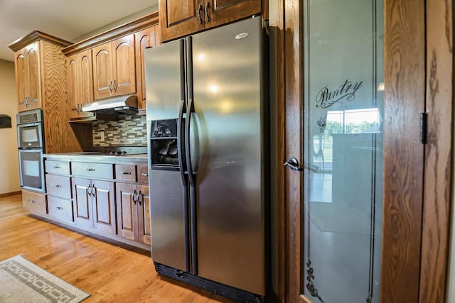 kitchen with light wood-type flooring, appliances with stainless steel finishes, and backsplash