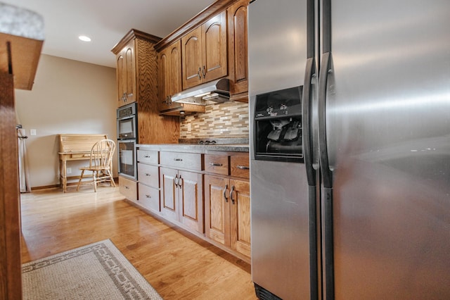 kitchen featuring light wood-type flooring, stainless steel appliances, and decorative backsplash