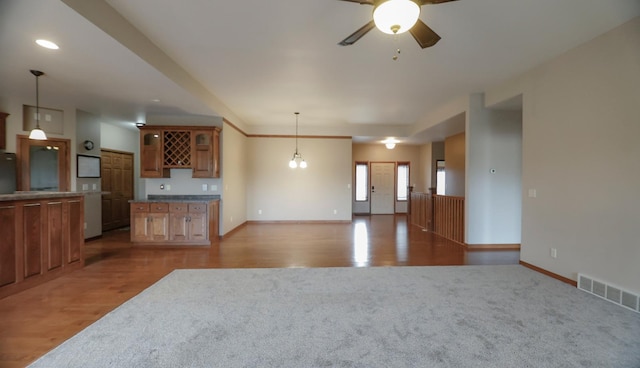 unfurnished living room featuring ceiling fan with notable chandelier and light hardwood / wood-style floors