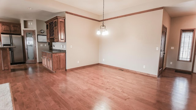 kitchen featuring stainless steel refrigerator with ice dispenser, wood-type flooring, and an inviting chandelier