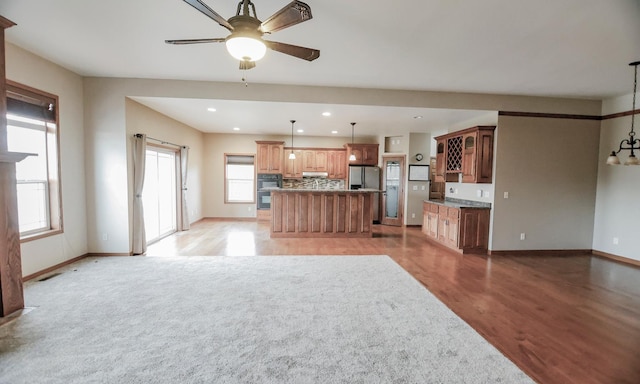 kitchen with a center island, a healthy amount of sunlight, stainless steel fridge, and light hardwood / wood-style floors