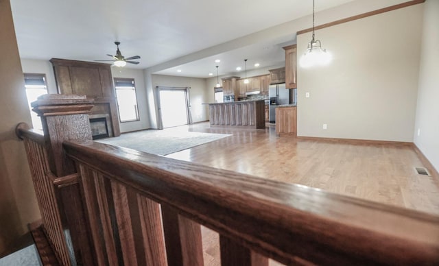 kitchen with stainless steel fridge, wood-type flooring, a center island, and ceiling fan