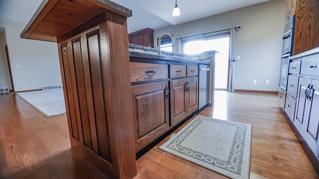 kitchen with light wood-type flooring, hanging light fixtures, appliances with stainless steel finishes, and sink