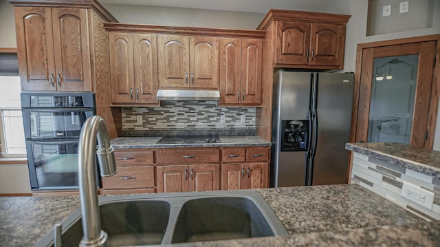 kitchen with black appliances, dark stone countertops, sink, and backsplash