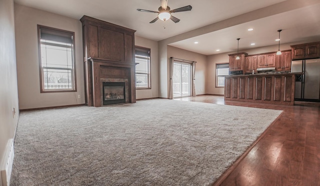 unfurnished living room with a large fireplace, ceiling fan, and hardwood / wood-style flooring