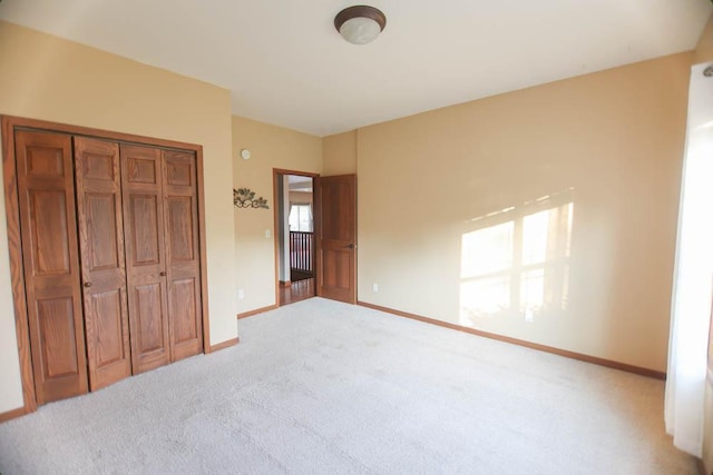 unfurnished bedroom with light colored carpet and a closet