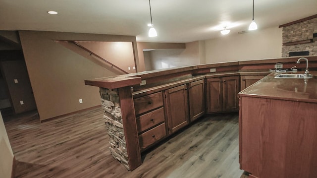 kitchen featuring pendant lighting, an island with sink, hardwood / wood-style floors, and sink