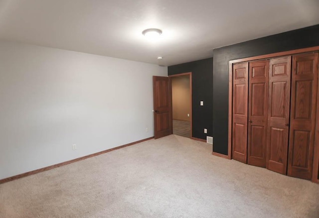 unfurnished bedroom with a closet and light colored carpet