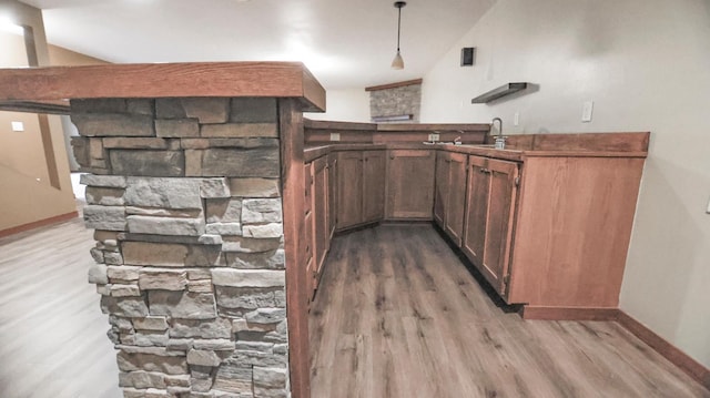 kitchen with lofted ceiling, hanging light fixtures, wood-type flooring, and sink