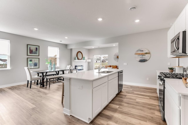 kitchen featuring sink, plenty of natural light, an island with sink, stainless steel appliances, and white cabinets