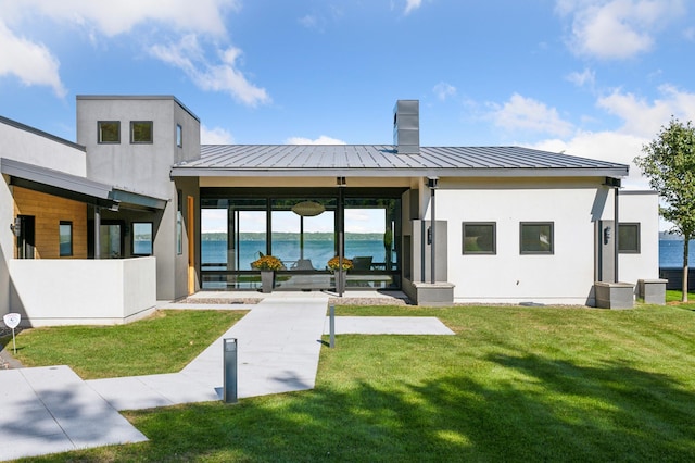 rear view of house with a water view and a lawn