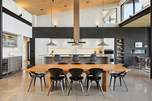 kitchen featuring high vaulted ceiling, wood ceiling, stainless steel double oven, hanging light fixtures, and white cabinetry