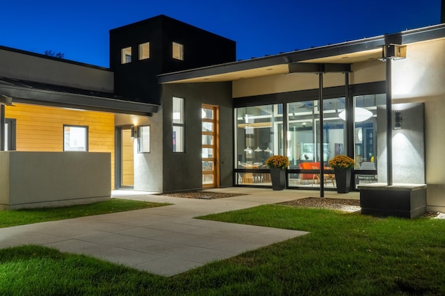 back house at twilight featuring a yard