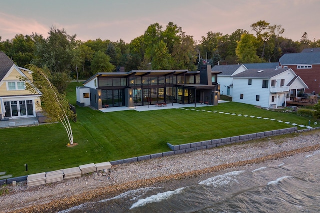 back house at dusk with a sunroom and a yard