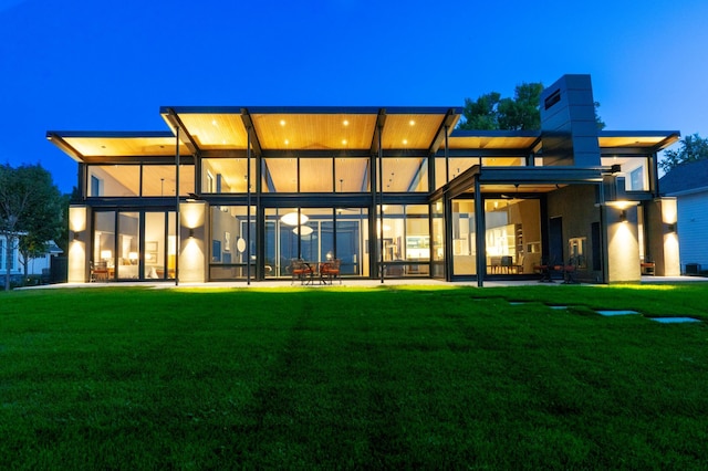 back house at dusk with a yard and a patio