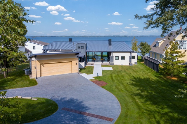 view of front of house with a garage, a front lawn, and a water view