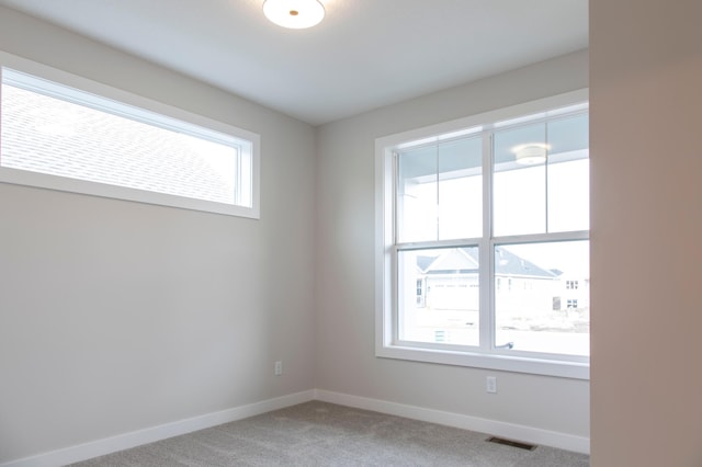 unfurnished room featuring visible vents, light colored carpet, and baseboards