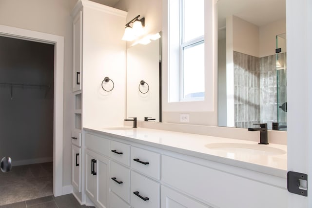 full bathroom featuring a sink, an enclosed shower, a spacious closet, and double vanity