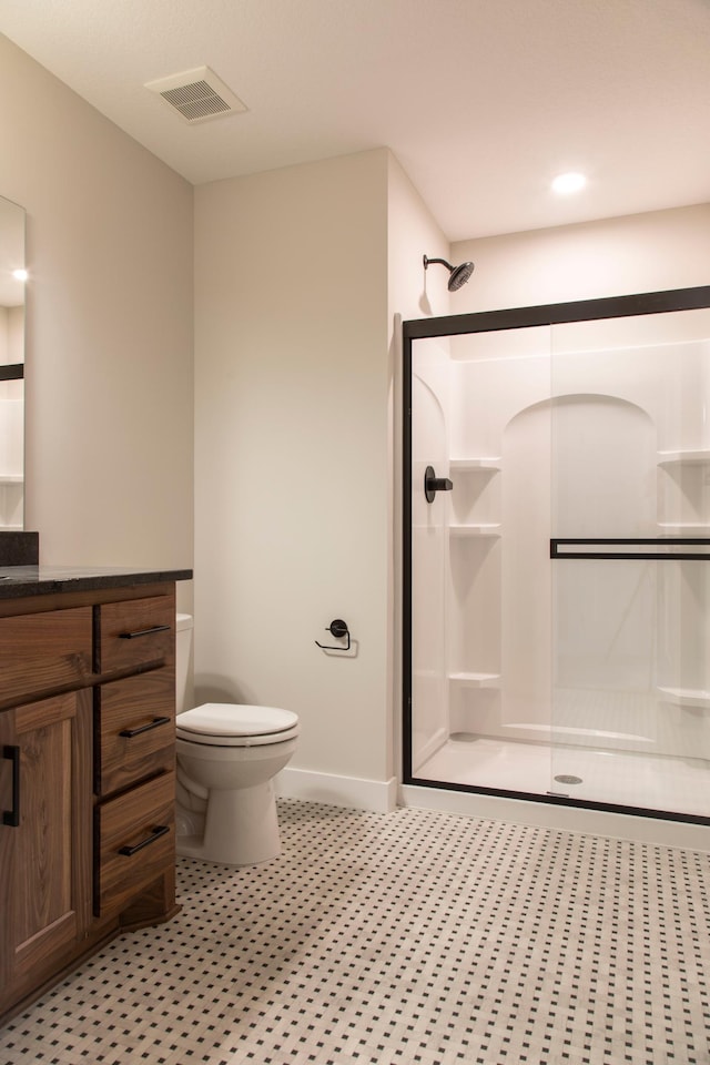 bathroom with vanity, a shower stall, toilet, and visible vents