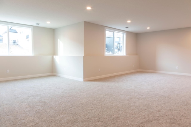 spare room featuring light carpet, recessed lighting, and baseboards