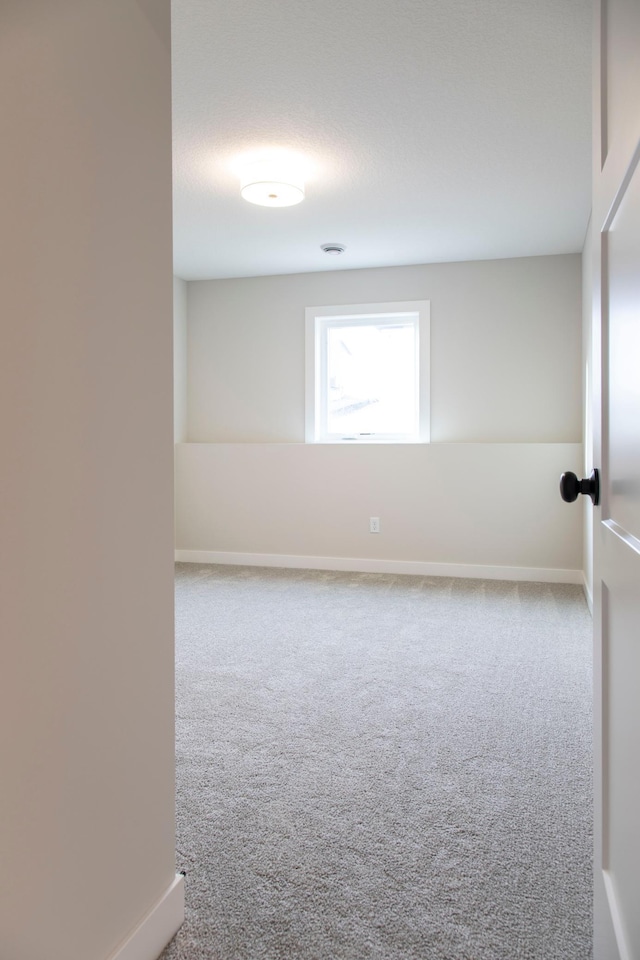 carpeted spare room featuring baseboards