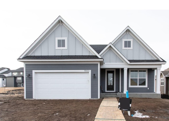 view of front of house with board and batten siding, an attached garage, and roof with shingles