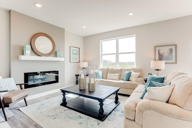 living room with a glass covered fireplace, light wood-style flooring, and recessed lighting