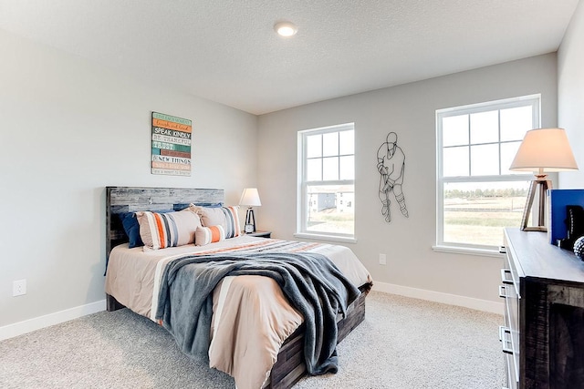 bedroom featuring multiple windows, a textured ceiling, and baseboards