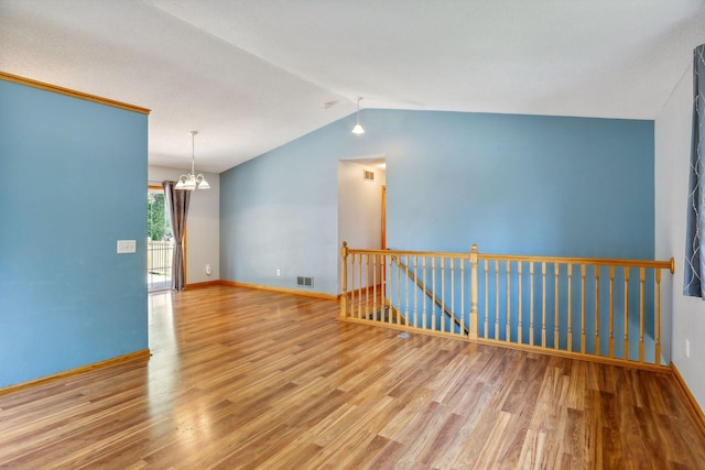 unfurnished room featuring vaulted ceiling, a notable chandelier, and hardwood / wood-style floors