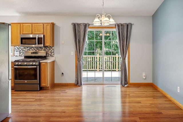 kitchen featuring light wood-type flooring, hanging light fixtures, stainless steel appliances, and a chandelier