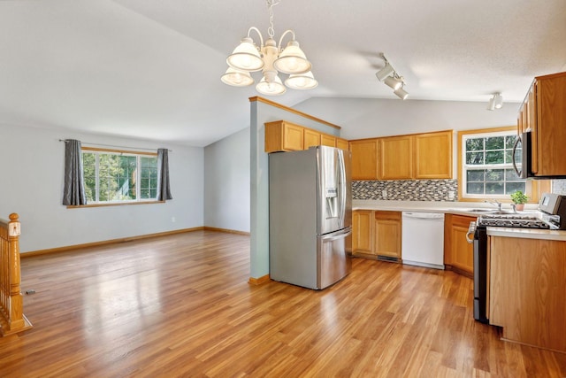 kitchen with backsplash, an inviting chandelier, appliances with stainless steel finishes, light hardwood / wood-style floors, and pendant lighting