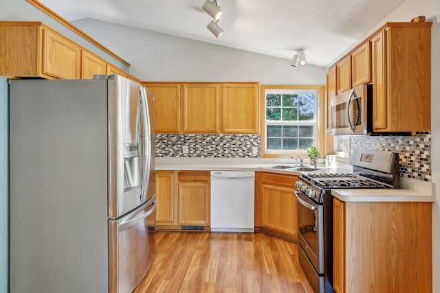 kitchen featuring backsplash, light hardwood / wood-style flooring, vaulted ceiling, and appliances with stainless steel finishes