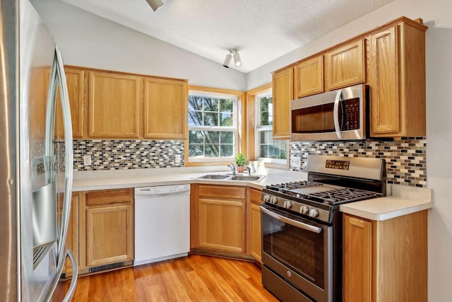 kitchen featuring vaulted ceiling, sink, appliances with stainless steel finishes, and tasteful backsplash